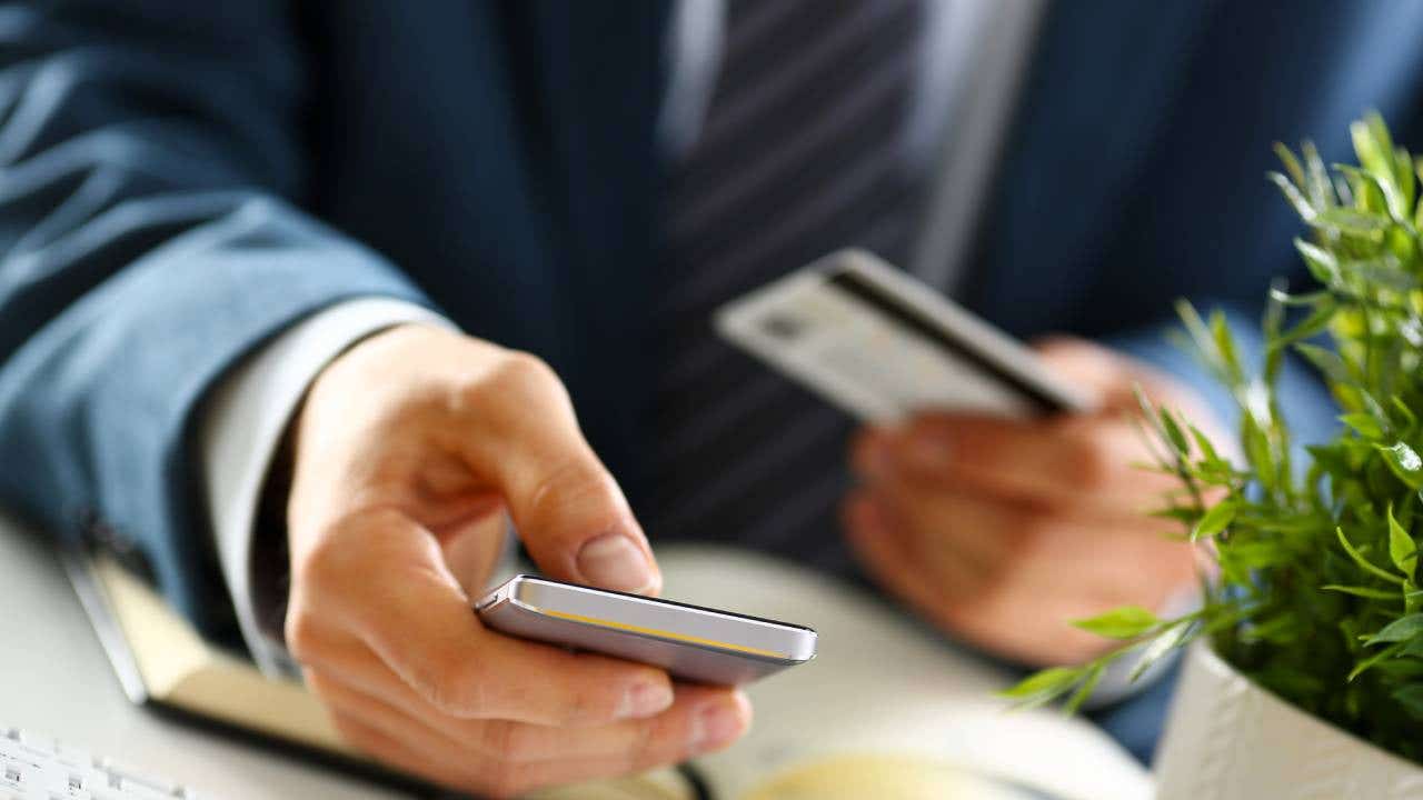 Male arms in suit hold credit card and phone