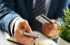 Male arms in suit hold credit card and phone