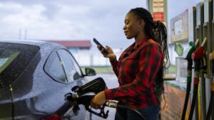 Woman using her phone while pumping cas \