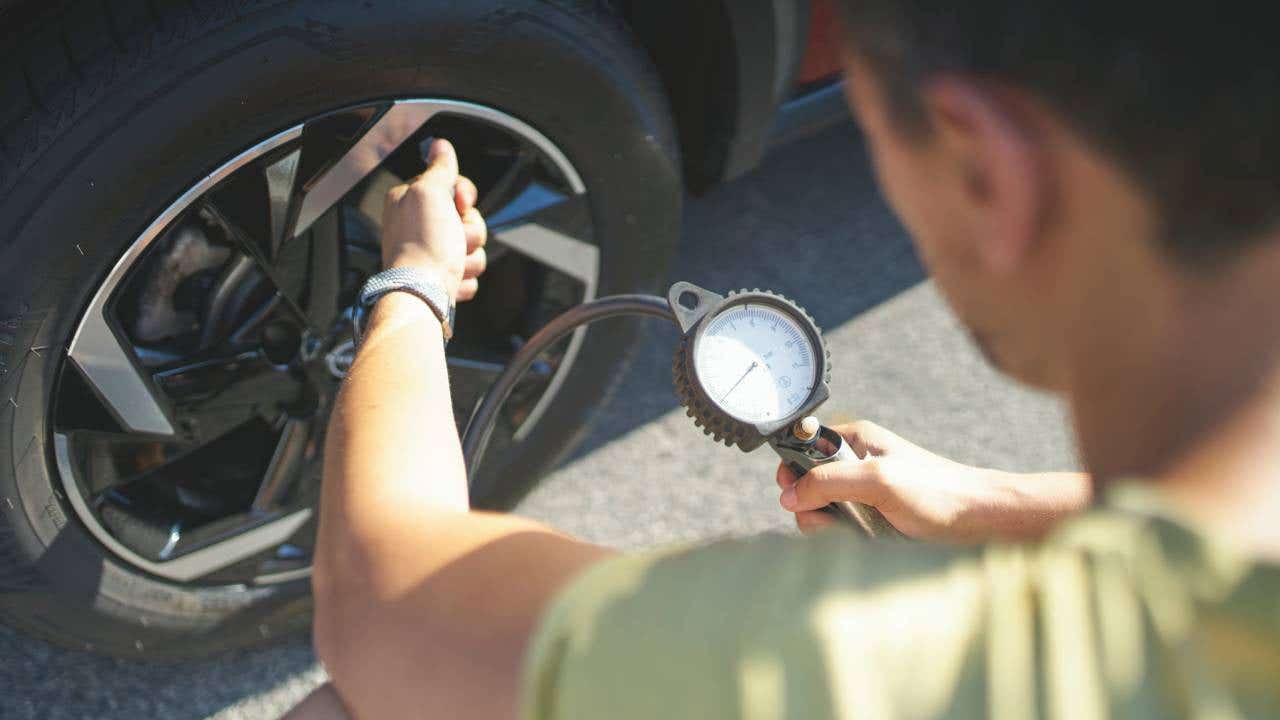 Rear view of man inflating tires of his car