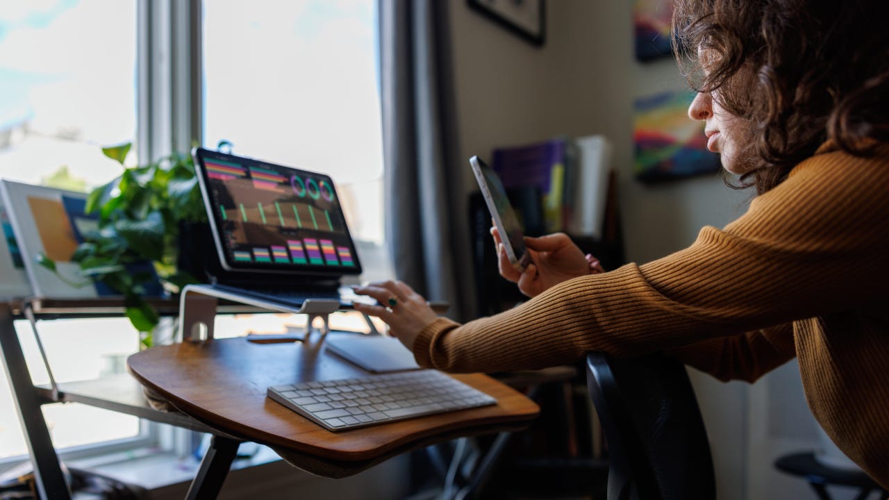 Asesora charlando con sus clientes y revisando gráficos de divisas en su computadora portátil desde casa.