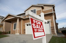 tan house with white trim and red "for sale by owner" sign out front