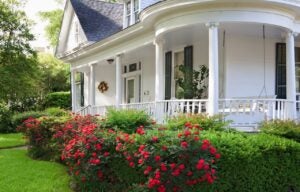 front porch of white Alabama home with porch swing and roses