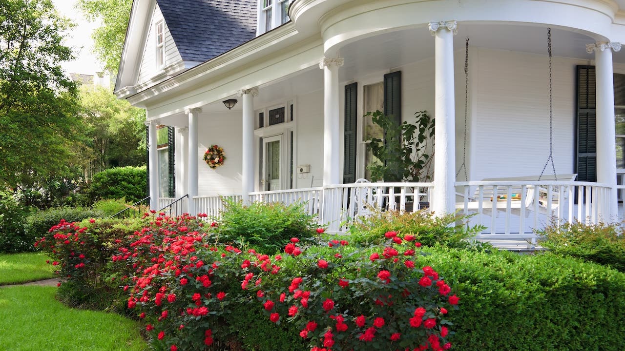 front porch of white Alabama home with porch swing and roses