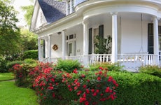 front porch of white Alabama home with porch swing and roses