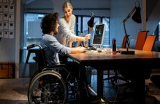 A man and a woman look at and discuss graphs on a computer screen.