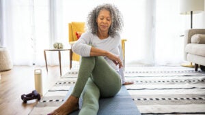 Senior woman stretching and exercising in living room