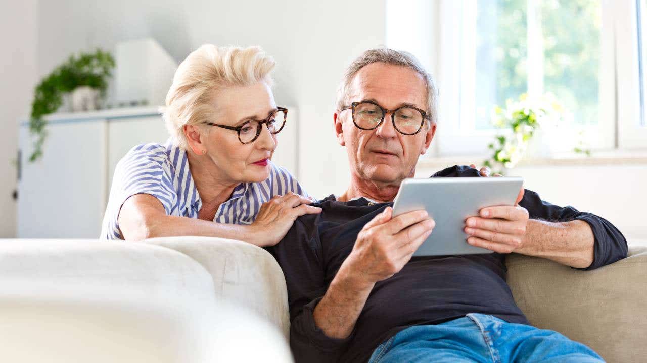 A senior couple looking at a digital tablet together at home.