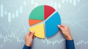 Two hands putting together pieces of a pie chart divided into five differently sized segments.