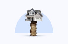 A house sitting atop a stack of coins