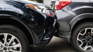 Close-up of a collision between two cars with the front end of one car and the back of another slightly crushed.