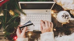 Woman using credit card to shop online, close up