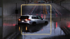 An SUV sits in the middle of a deep pool of water during a storm.