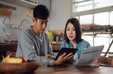 An Asian couple planning finances with a digital tablet at home.