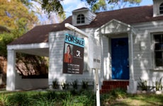 White suburban house with blue door and "for sale" sign out front