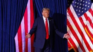 President-elect Donald Trump onstage at a rally with American flags displayed behind him.