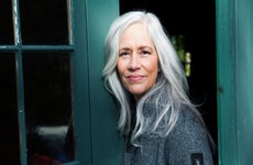 Woman in her late 50s with long, silver white hair outside smiling