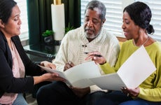 An older Black couple discusses paperwork with a female advisor.