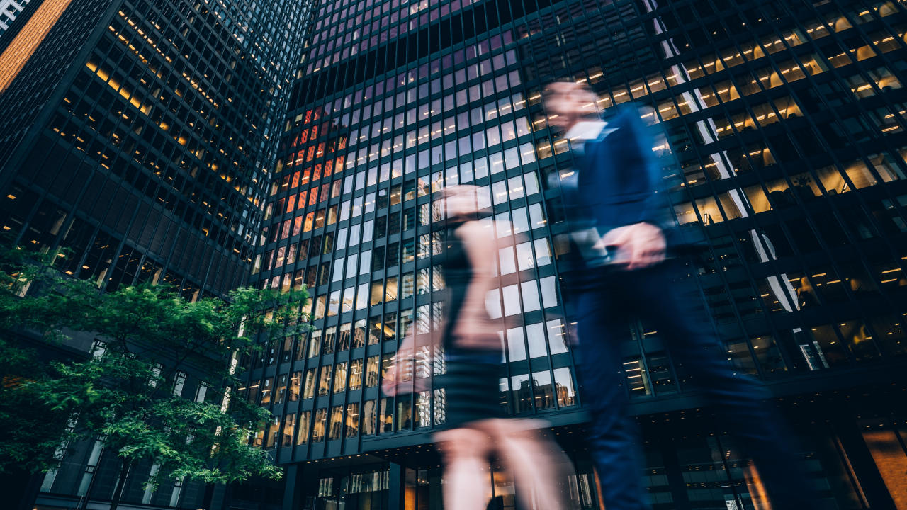 Two business people walking on downtown street. Blurred motion effect.