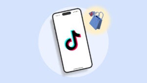 Image of a phone featuring the TikTok logo. There is a bag with a price tag to the side of it. The images are on top of a white circle with a light blue background.