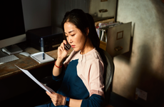 Portrait of woman on cell phone reading important document - stock photo