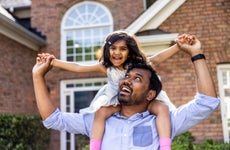 Smiling Indian-American man carries daughter on shoulder