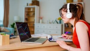 Person wearing headphones and looking at laptop displaying a stock chart.