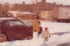 Aged photo of young girl with parent on snowy street