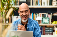 Mature man laughing and smiling on video conference - stock photo