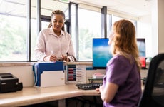 Female patient paying with credit card at doctor's office front desk