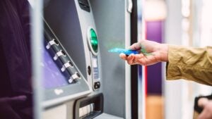 Female hand inserting bank card into ATM