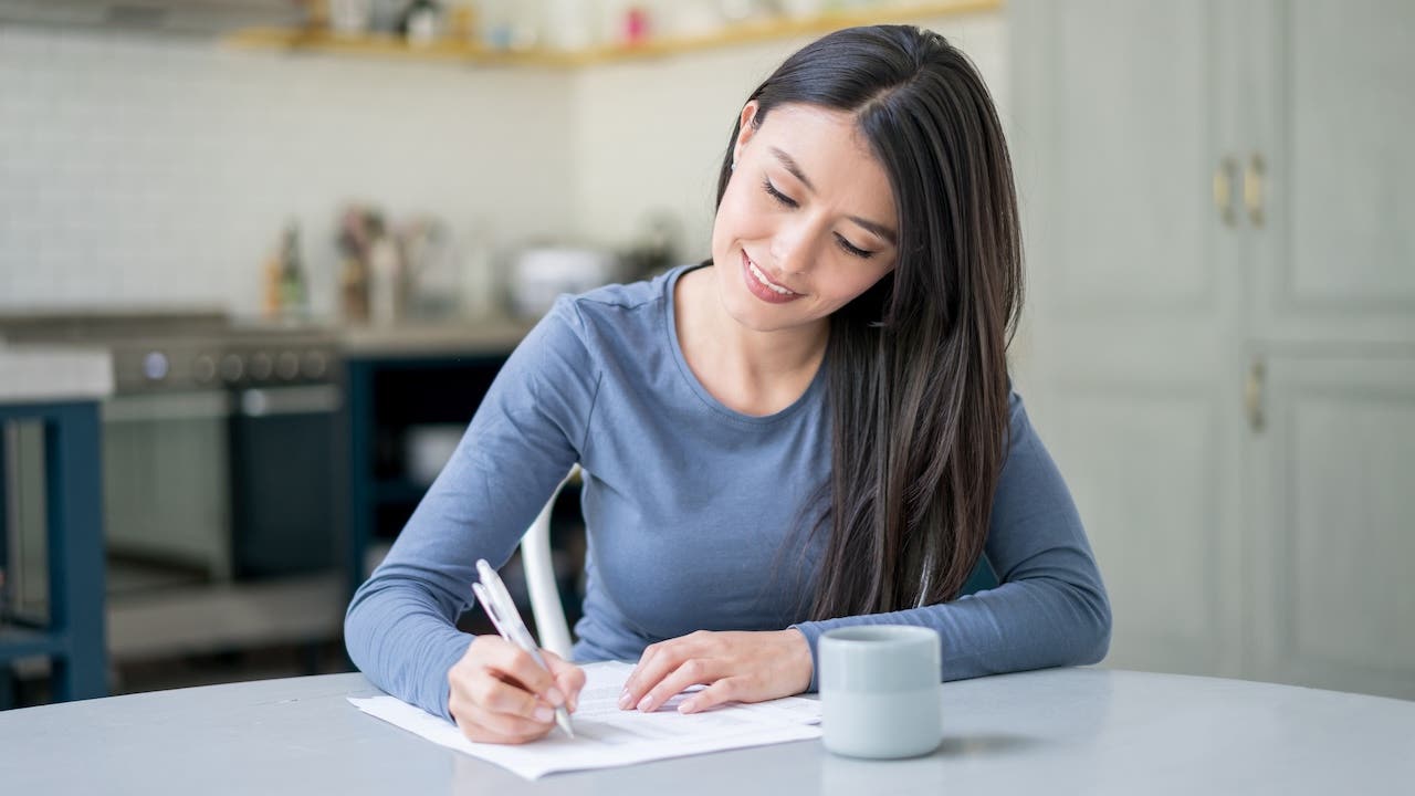 Casual woman at home writing a letter