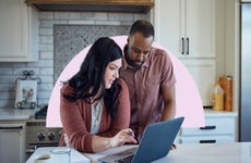 Man and woman standing at kitchen counter looking at laptop