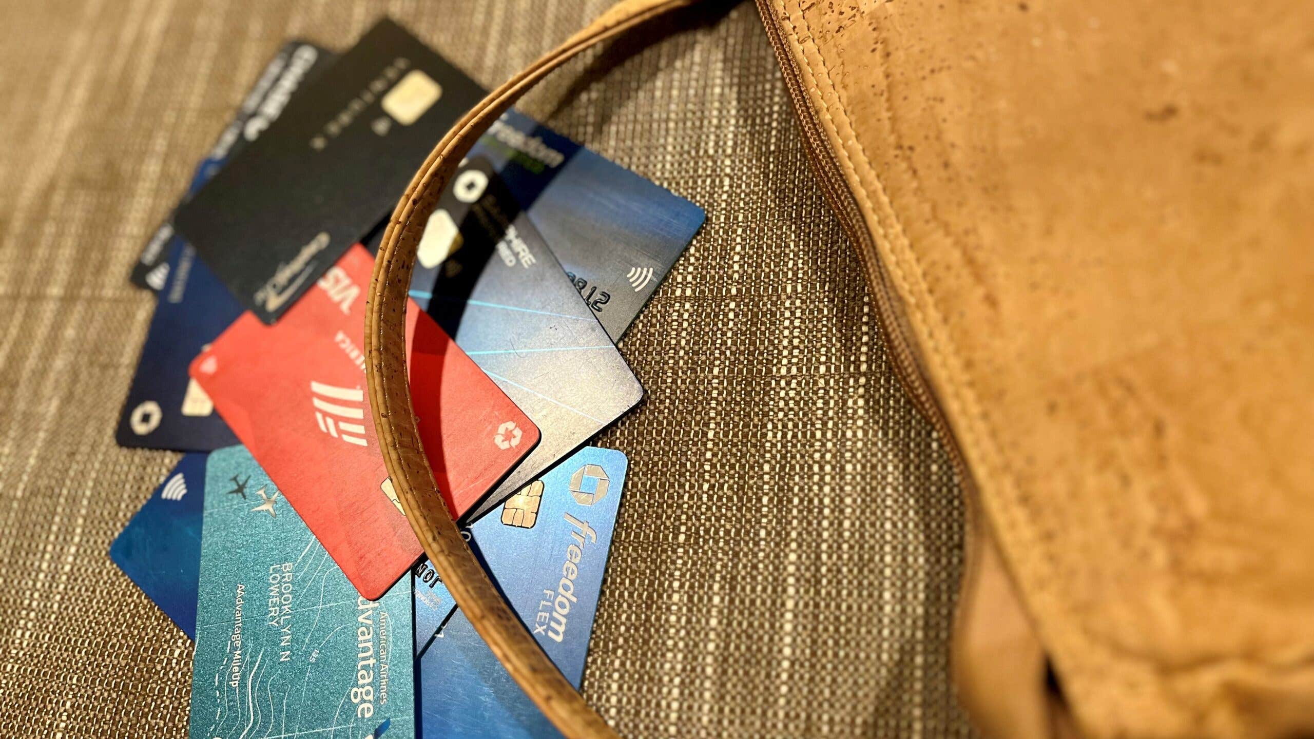 A pile of credit cards beside a brown purse