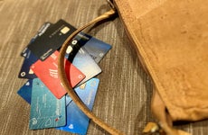 A pile of credit cards beside a brown purse