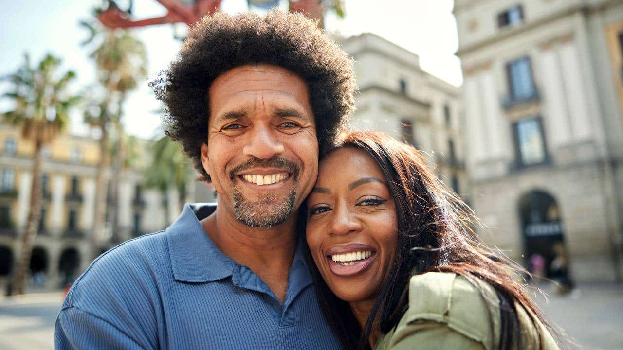 A portrait of a smiling couple in their 40s or 50s.