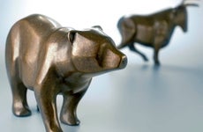 A bronze bear figurine stands in front of a bull figurine.