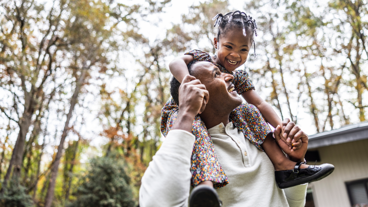 father with daughter on shoulders smiling and laughing