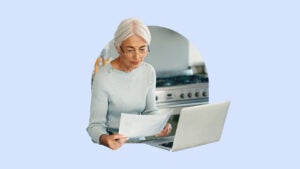 Older woman in glasses looking a her life insurance policy by a computer