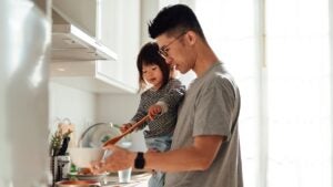 father holding daughter while cooking together