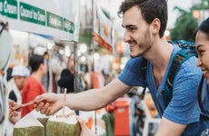 man and woman buying coconut water from a market stand