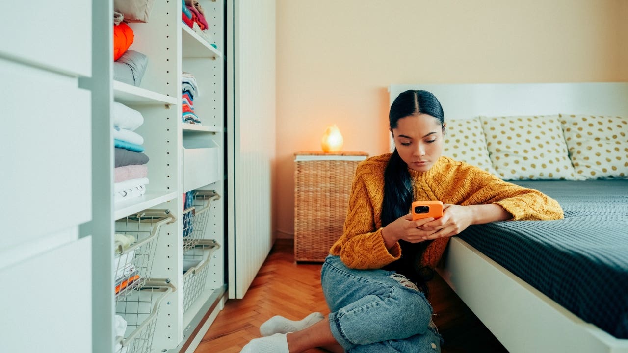 woman sitting on the floor of a room using her phone