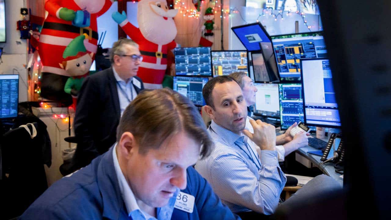 Three traders looking at various monitors with Christmas decorations in the background.