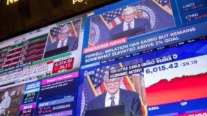 Multiple monitors displaying Federal Reserve Chair Jerome Powell speaking at a podium.