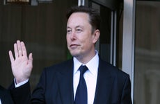 Businessman Elon Musk raises his hand in a wave.