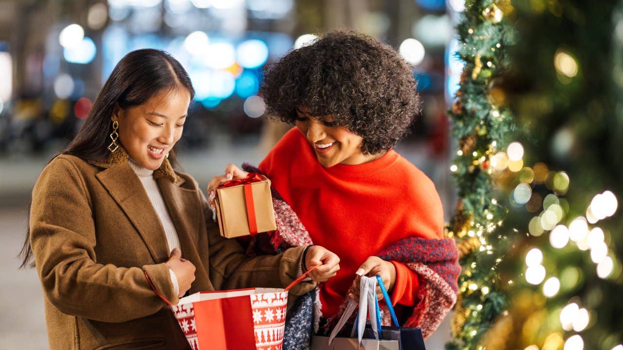 Two smiling young women exchanging gifts