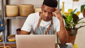 A stressed out man working on a laptop.