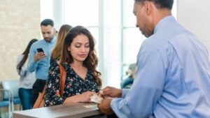 Woman getting cash from a male bank teller