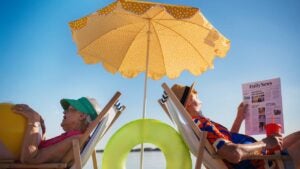 Portrait of a senior couple lying in beach chairs under a sun umbrella.