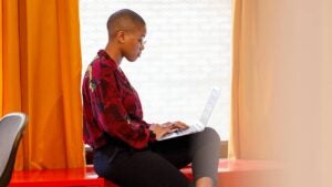 A woman works by the window on her computer.